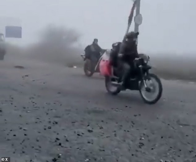 Some sat on the roofs of battered cars, while a drone was seen beside the road