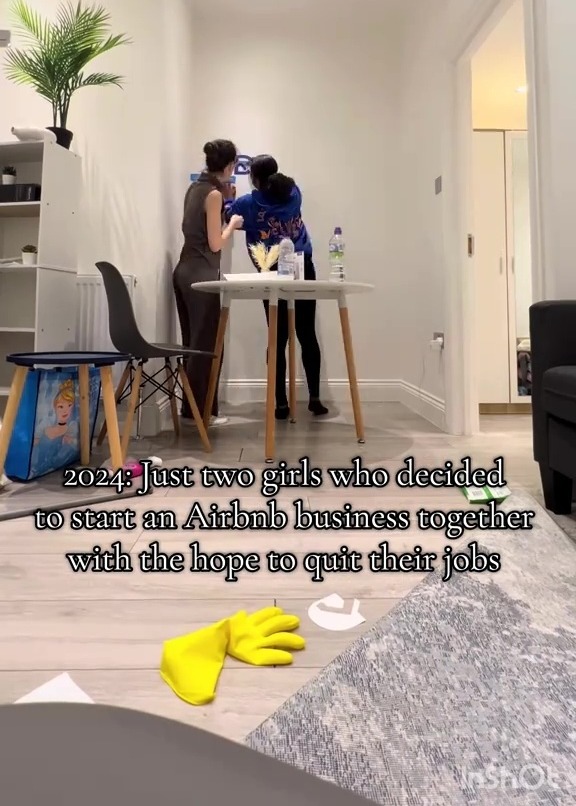Two young women working together to assemble something in a sparsely furnished room with the overlaid text "2024: Just two girls who decided to start an Airbnb business together with the hope to quit their jobs."
