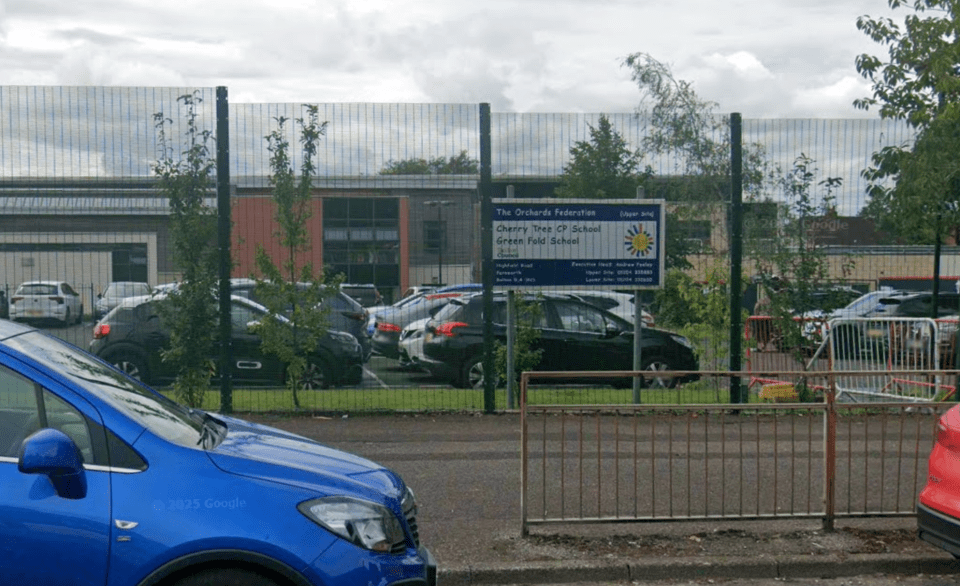 The Orchards Federation signage visible through a fence with cars in the foreground.