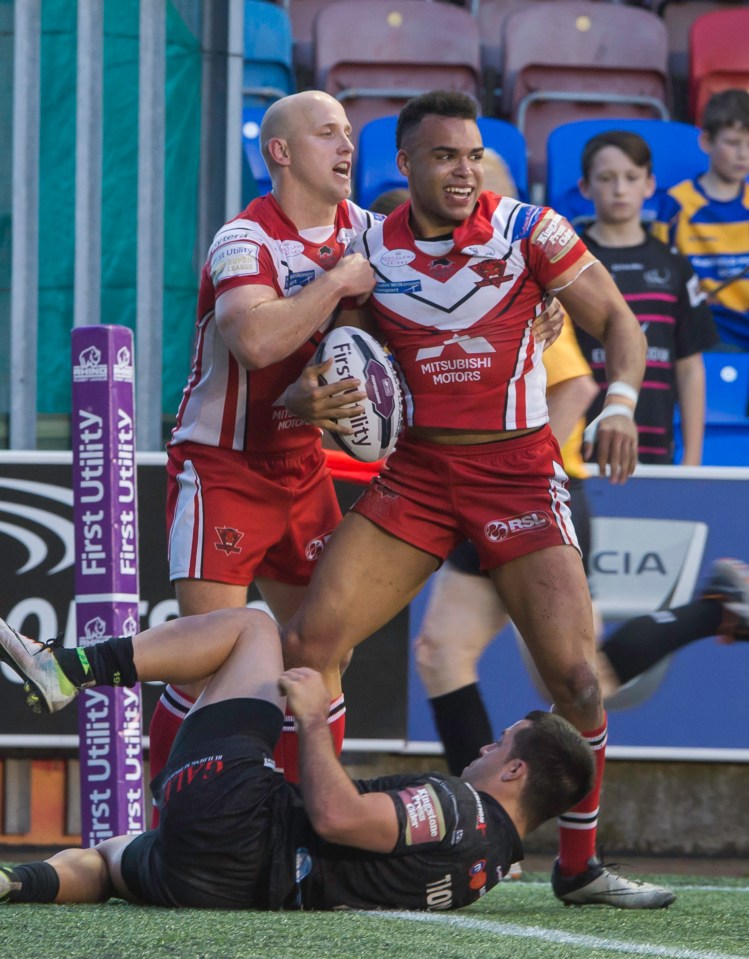 Rugby players Mason Caton-Brown and teammate celebrating a try over an opposing player.