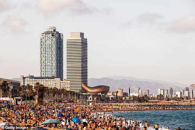 A throng of sun seekers covers the sand at Barceloneta beach in the Catalan city