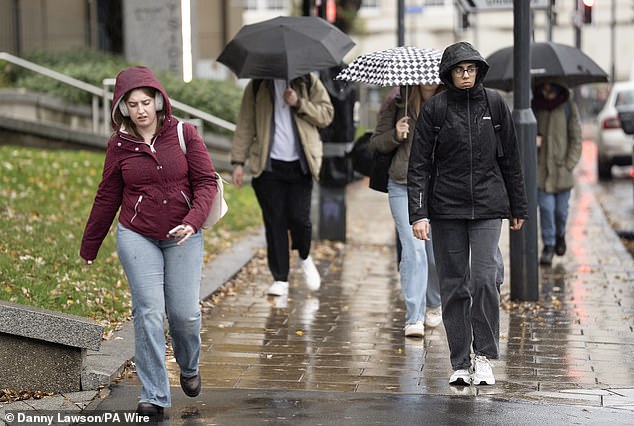 People walk in the rain in Leeds today after forecasters issued two amber warnings for rain