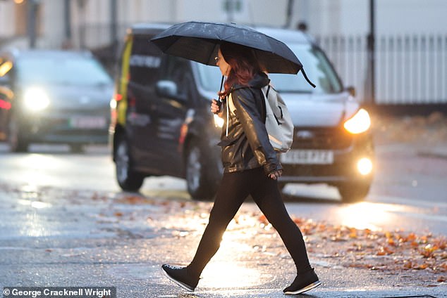 A commuter uses an umbrella during heavy rain near Euston station in London this morning