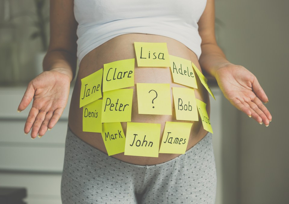 Pregnant woman with sticky notes of potential baby names on her belly.