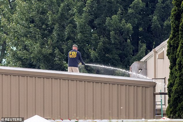 Photos from the day after the shooting show an FBI agent hosing down the site where Crooks died
