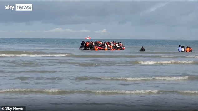 As the small boat begins to sail away, a man wearing a black tracksuit and cap is seen pretending to fall off the inflatable vessel, clearly not intending to travel