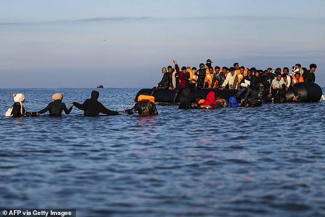 Migrants wade into the sea to try to board smugglers' boats in an attempt to cross the English Channel off the beach of Gravelines, northern France on September 27, 2025