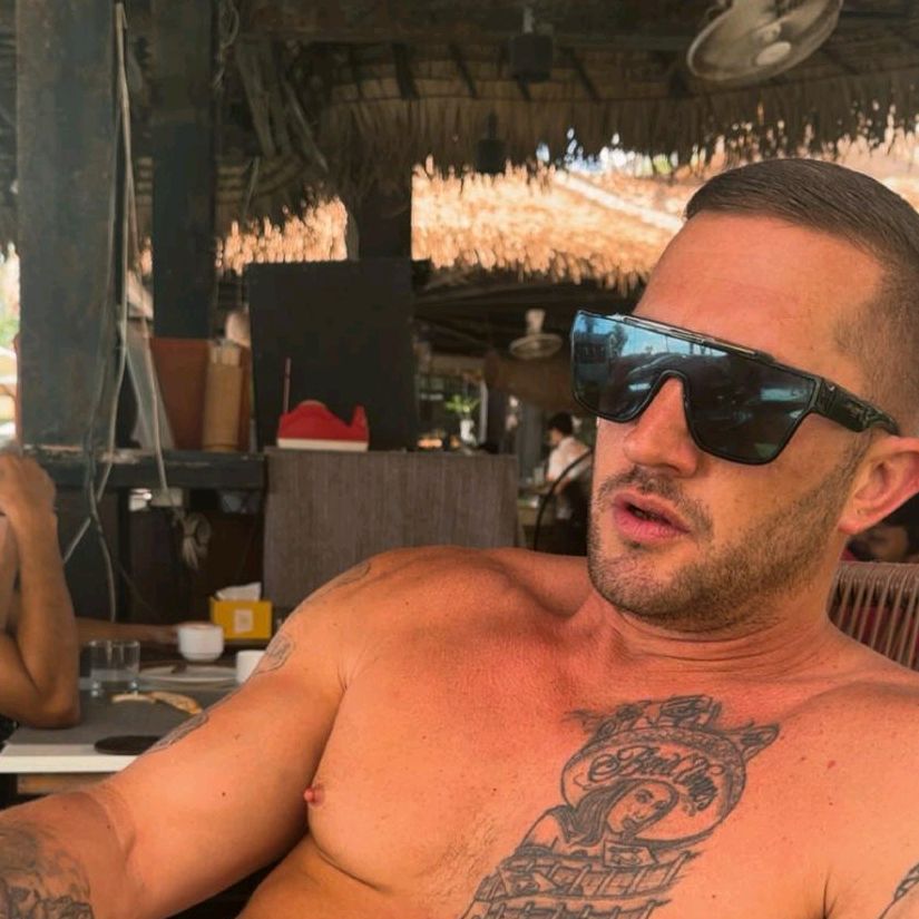 Daniel Harper (DannyBoy83) wearing sunglasses and showing a chest tattoo.