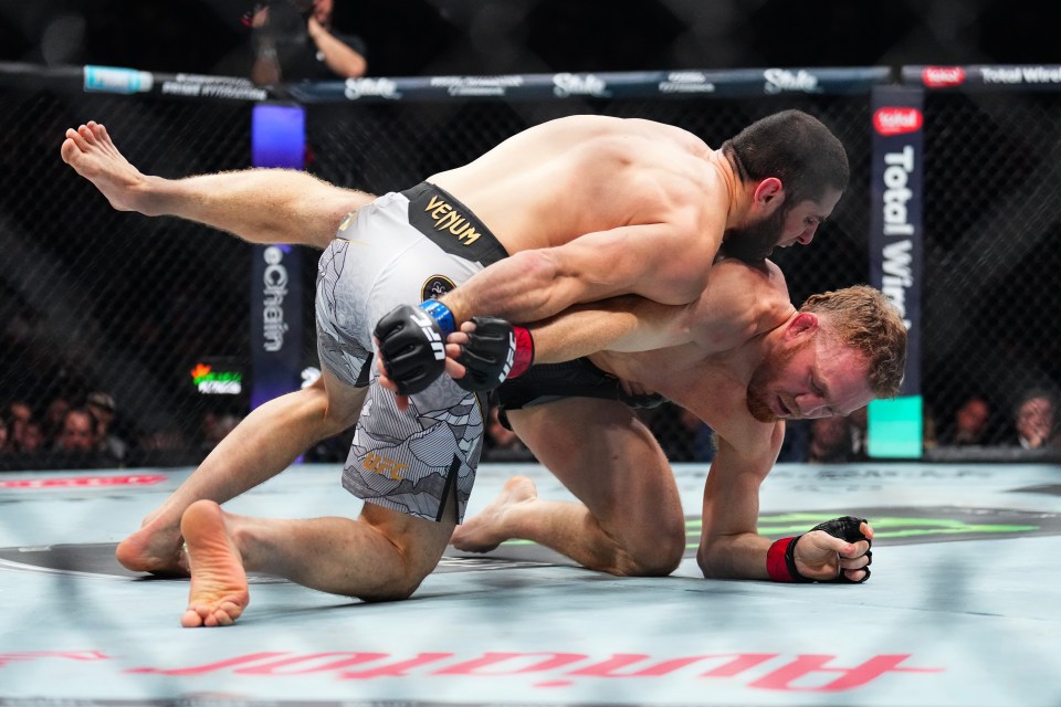 Islam Makhachev (red gloves) celebrates defeating Dustin Poirier (blue gloves) during UFC 302.