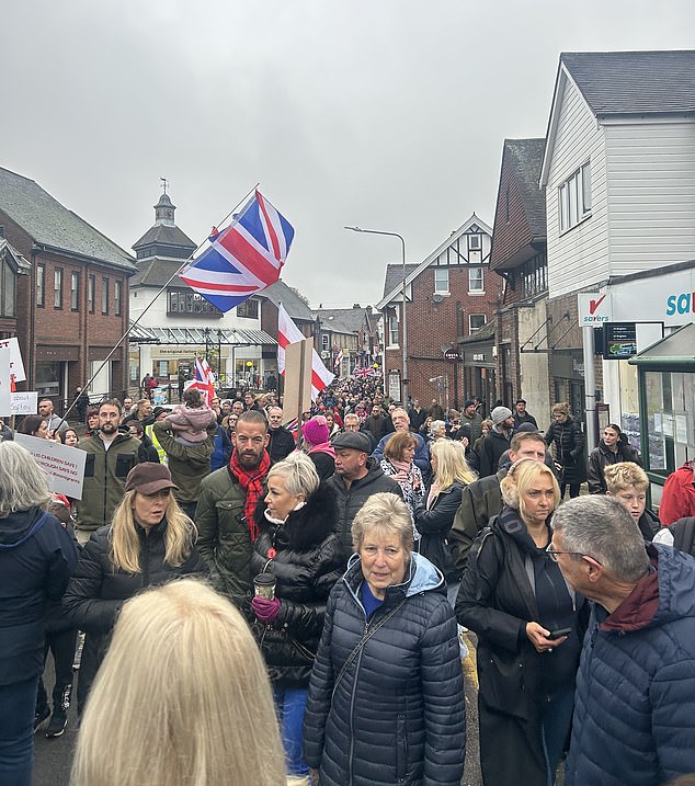 Protesters in Crowborough, East Sussex, hold placards and march through the town centre this morning over plans to house 600 male asylum seekers at Crowborough Training Camp