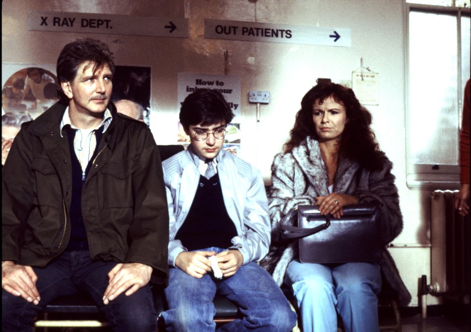 Stephen Moore, Gian Sammarco, and Julie Walters sitting in a waiting room, from the TV series "The Secret Diary of Adrian Mole".