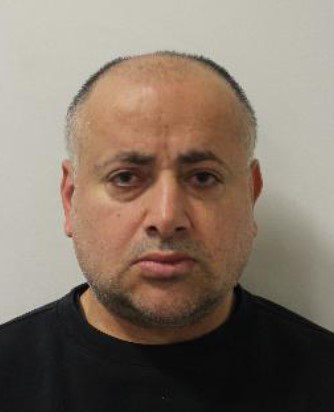 Mugshot of a man with dark, receding hair, a short beard, and dark eyes.