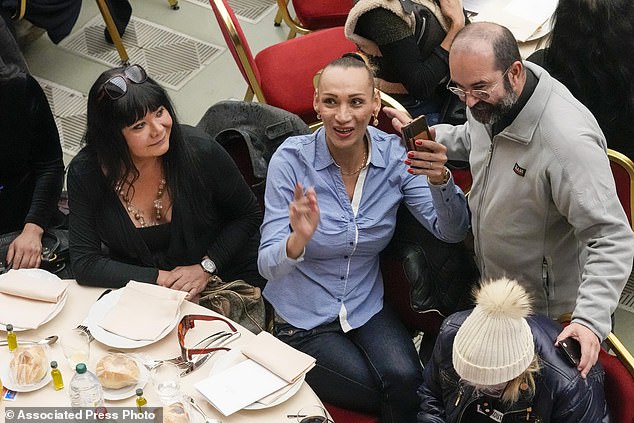 The woman had been seated on Pope Francis' table in previous years. Pictured, Priest Andrea Conocchia, right, with members of a group of transgender women he accompanied  in 2023