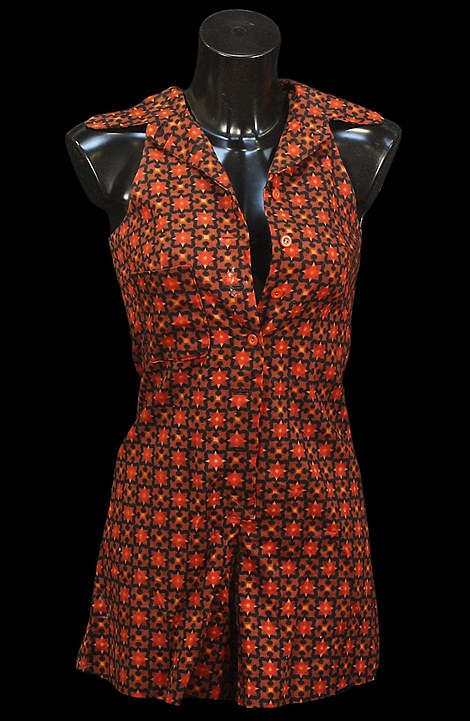 The playsuit has patterned orange and brown fabric, and is sleeveless with cutaway shoulders and a collar