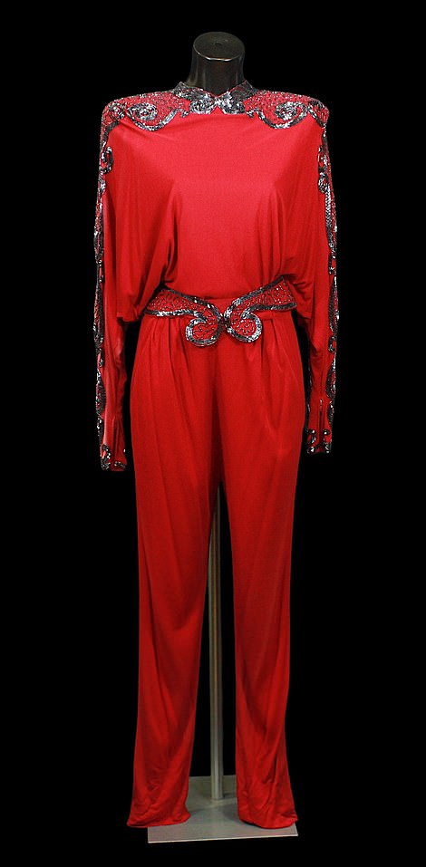The jumpsuit features synthetic fabric, embellished with coloured beads in a geometric pattern