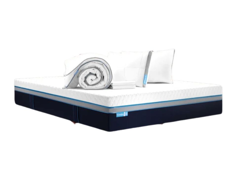 White mattress with dark blue sides, with a rolled-up white duvet and two white pillows on top.