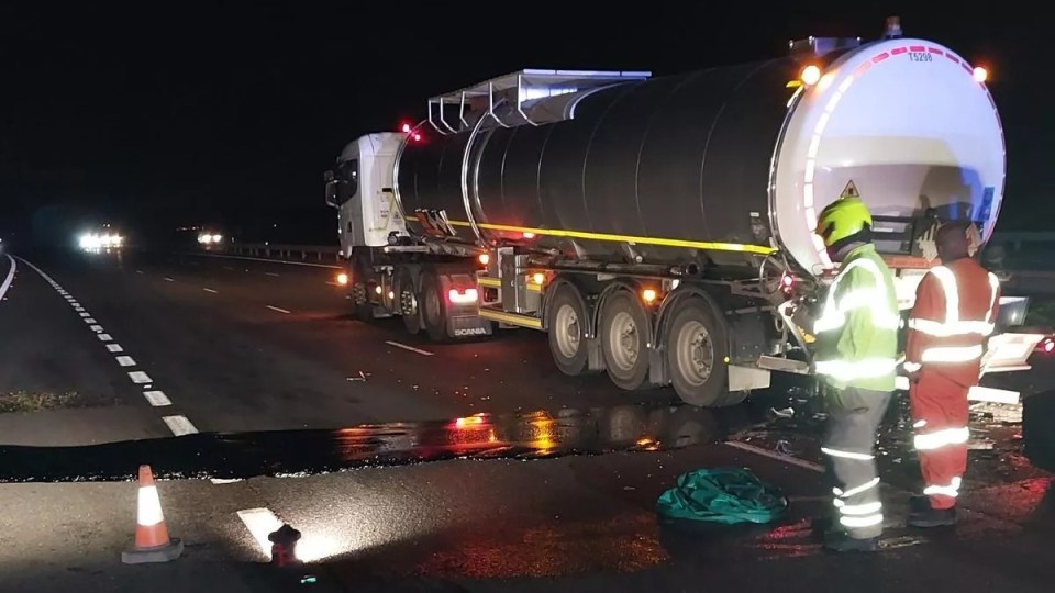 Tanker truck on a dark road with emergency personnel.