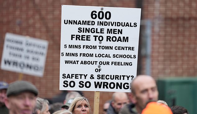 A sign held up at the protest read '600 unnamed individuals, single men, free to roam'