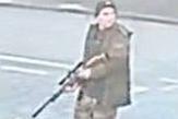Security camera footage of a male suspect in camouflage holding a rifle.