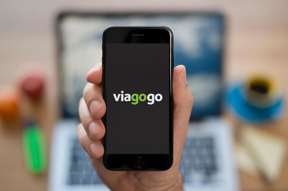 A hand holding an iPhone with the Viagogo logo on its screen.