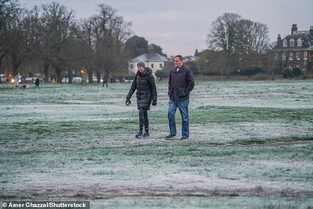 People walk across a frosty Wimbledon Common in South West London this morning