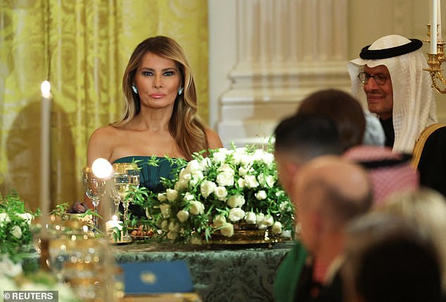 First Lady Melania Trump, seated at one of the three long tables in the East Room, wore a emerald gown that matched Saudi Arabia's flag and the table treatments