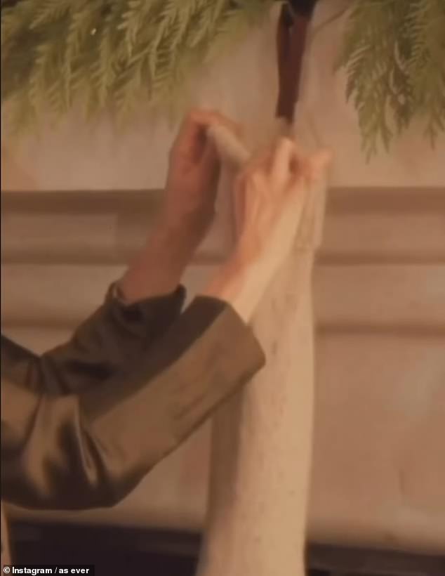 In the short video, Prince Harry's wife was seen popping a present into the brown stocking hung from her mantlepiece, then clasping her hands together and smiling