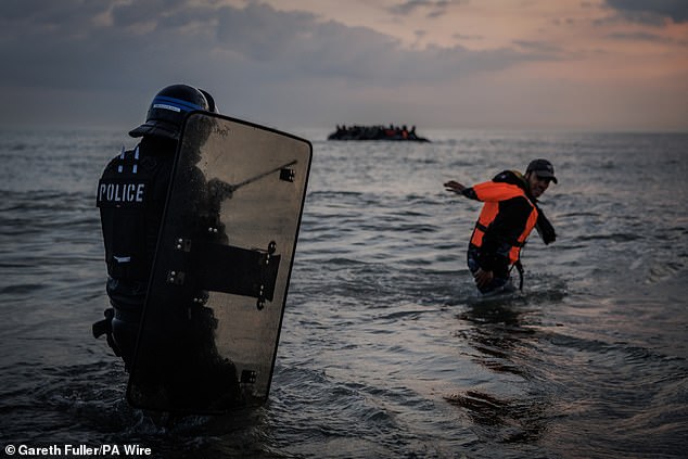 The drastic new method comes as more than 39,000 migrants have reached Britain this year in flimsy dinghies, piling pressure on Paris to stop departures from its northern beaches. Pictured: French police officers inspect a deflated small boat discarded by people thought to be migrants on the beach in Gravelines