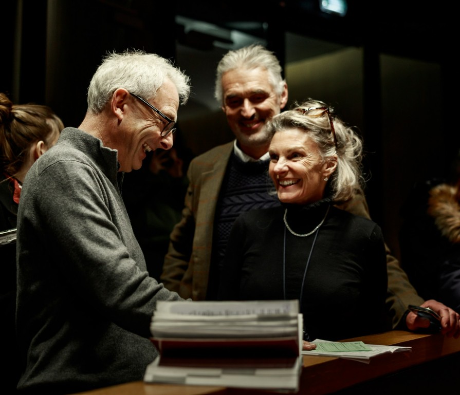 Three adults smiling and talking.