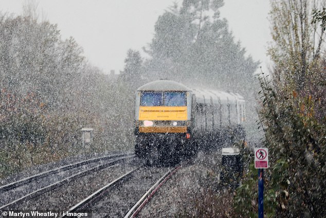 A train is driven through the snow near Northolt in west London this morning