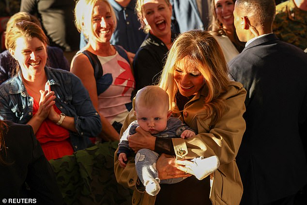 U.S. first lady Melania Trump holds a child as she and second lady Usha Vance meet with military service members and their families at Marine Corps Air Station New River