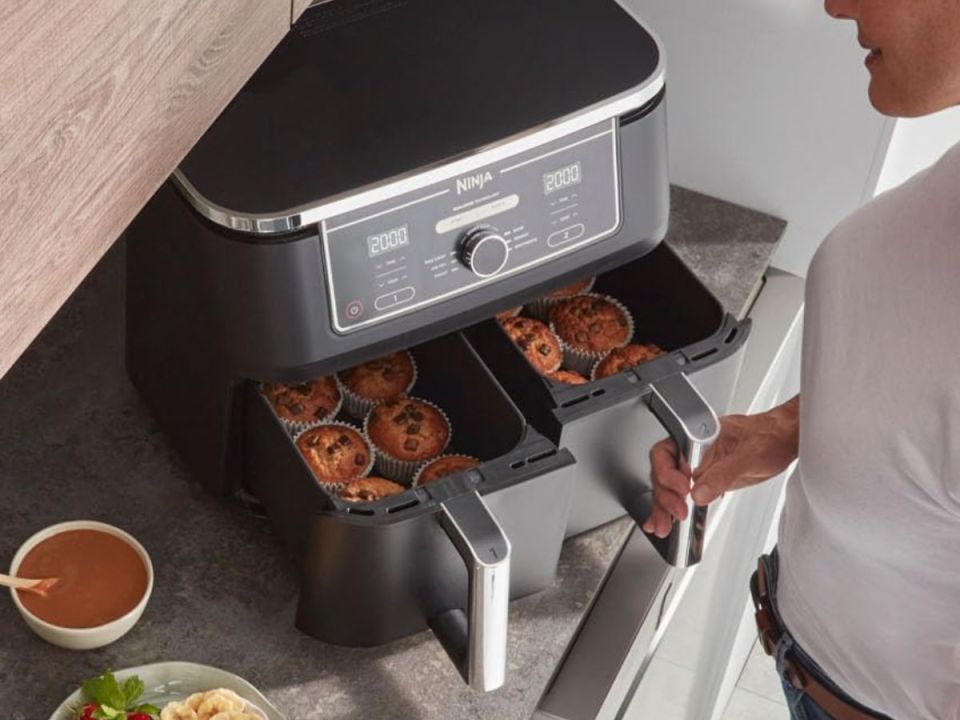 A person removes muffins from a Ninja double air fryer.