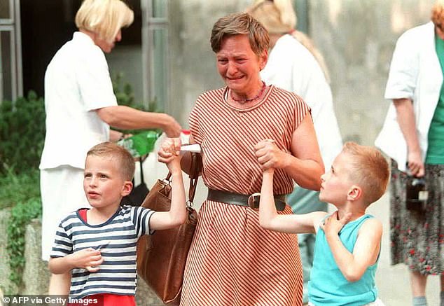 A young boy looks up at his crying mother as they leave Sarajevo's Kosevo hospital after her husband was wounded by a shell, 1995