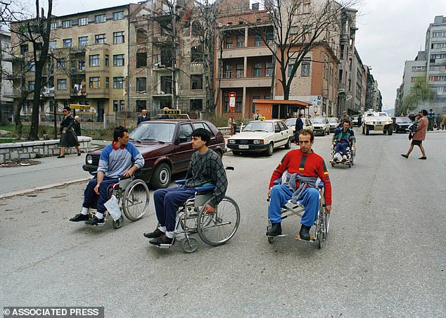 Paraplegics roll past the taxi rank near Tito Street in Downtown Sarajevo, 1994, a grim reminder of the brutality of war