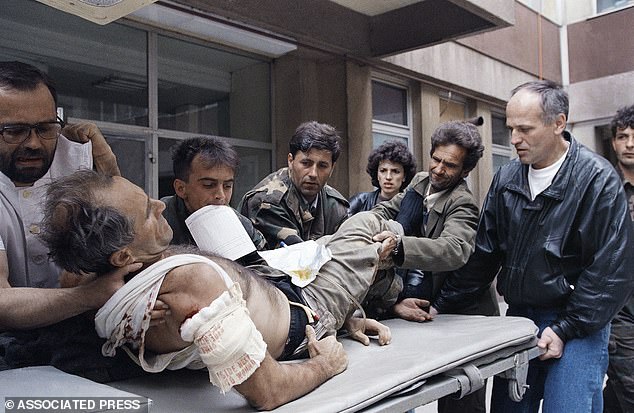 Doctors at Sarajevo's State Hospital carry Mujo Causevic, a Bosnian Army soldier wounded by sniper fire on one of Sarajevo's front lines, to be treated, 1995