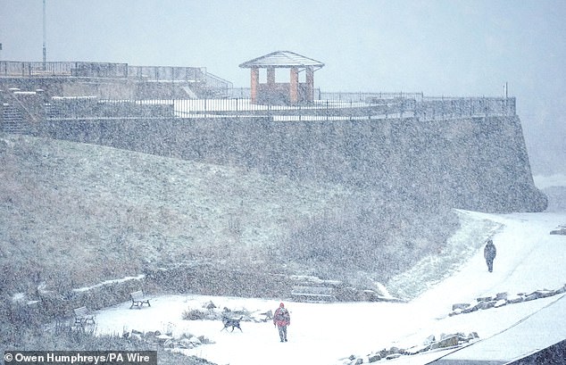 People walking in the snowy conditions at Cullercoats in North Tyneside this morning