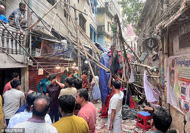 Residents stand in an alley after vacating their house next to a fallen scaffolding following an earthquake in Dhaka, Bangladesh, November 21, 2025