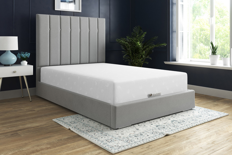 Gray upholstered bed frame with a white mattress in a bedroom.