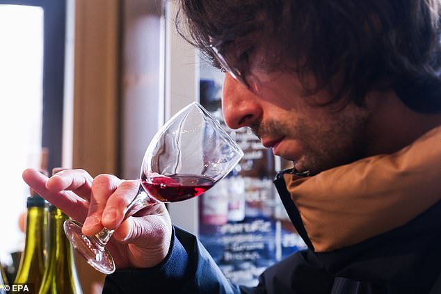 A man smells a glass of Beaujolais at a grocery store in Montreuil, Paris on Thursday