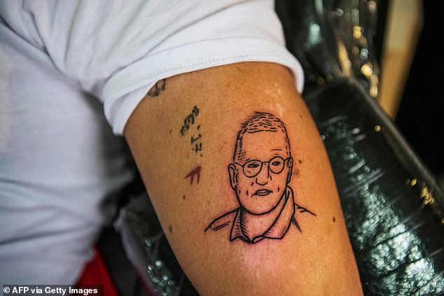 The now 69-year-old became a cult figure in the country, with his face printed on T-shirts, soaps and mugs. Others even sported Tegnell tattoos. Pictured, then 32-year-old Gustav Lloyd Agerblad presenting his new tattoo in April 2020