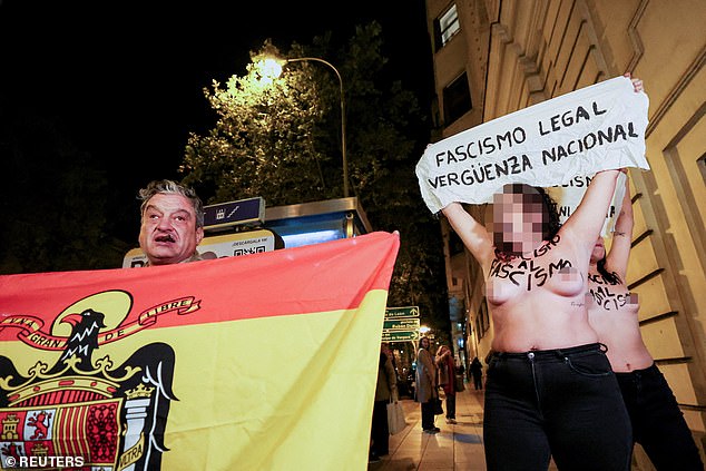 A counter-protester holds a flag next to activists from the feminist group Femen during a protest on the 50th anniversary of Spain's late dictator Francisco Franco's death, in Madrid, Spain, November 20, 2025