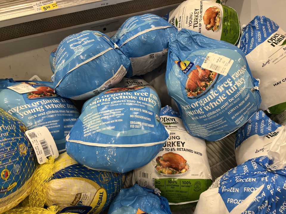 Frozen turkeys for sale in a supermarket refrigerated display.