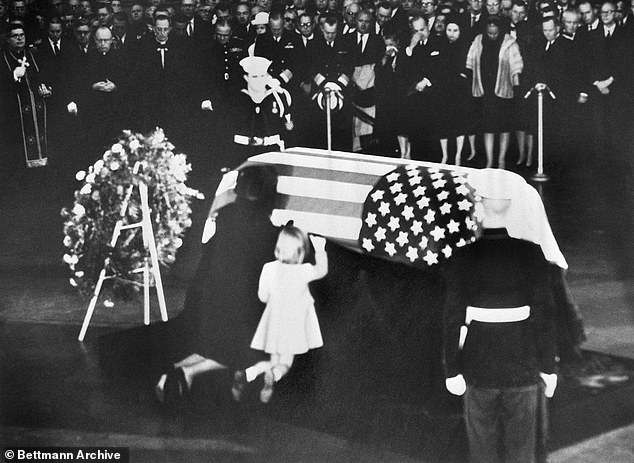 Jacqueline and Caroline Kennedy, wife and daughter of Kennedy, kneel at his coffin