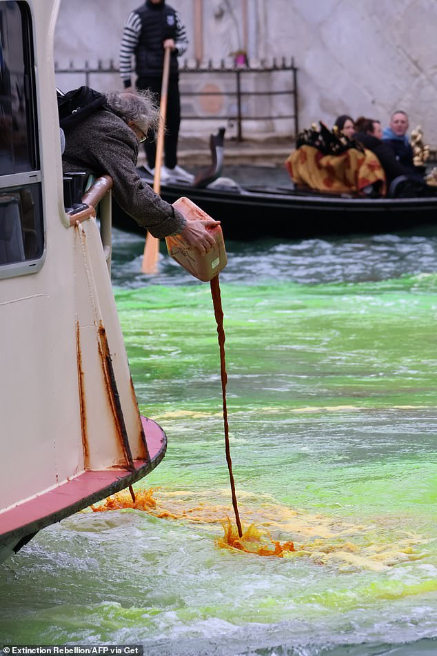 An Extinction Rebellion activist pouring an environmentally harmless dye into Venice's Grand Canal, turning it green