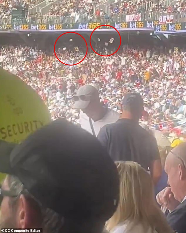 Another video on X showed beer cups and trays raining down from the upper levels of the stands (circled) as a security guard (left) went through the crowd as a warning about spectator behaviour flashed up on the big screen