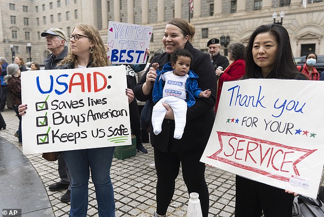 United States Agency for International Development (USAID) supporters hold banners as workers retrieve their personal belongings from the USAID's headquarters in Washington
