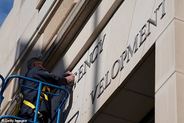 A worker removes the US Agency for International Development (USAID) sign on their headquarters in February in Washington, DC