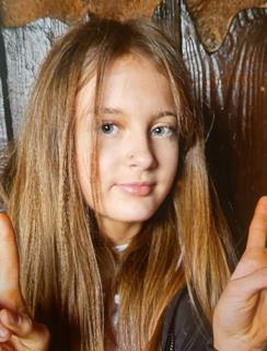 A missing girl, Emily, with long brown hair, looking at the camera.