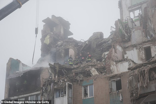 Rescuers pause search-and-rescue operations at a multi-story residential building, destroyed by the Russian missile strike to observe a moment of silence for the strike victims on November 21, 2025 in Ternopil, Ukraine