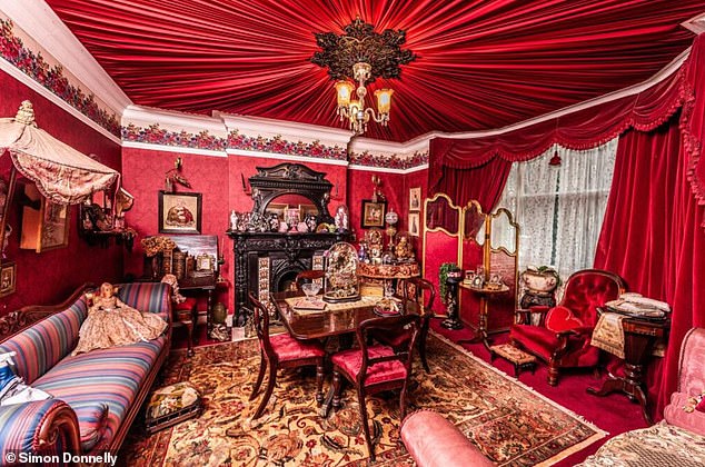 The formal front reception room boasts a commanding bay window, high ceilings and a meticulously restored period fireplace within the confines of a bold crimson colour scheme